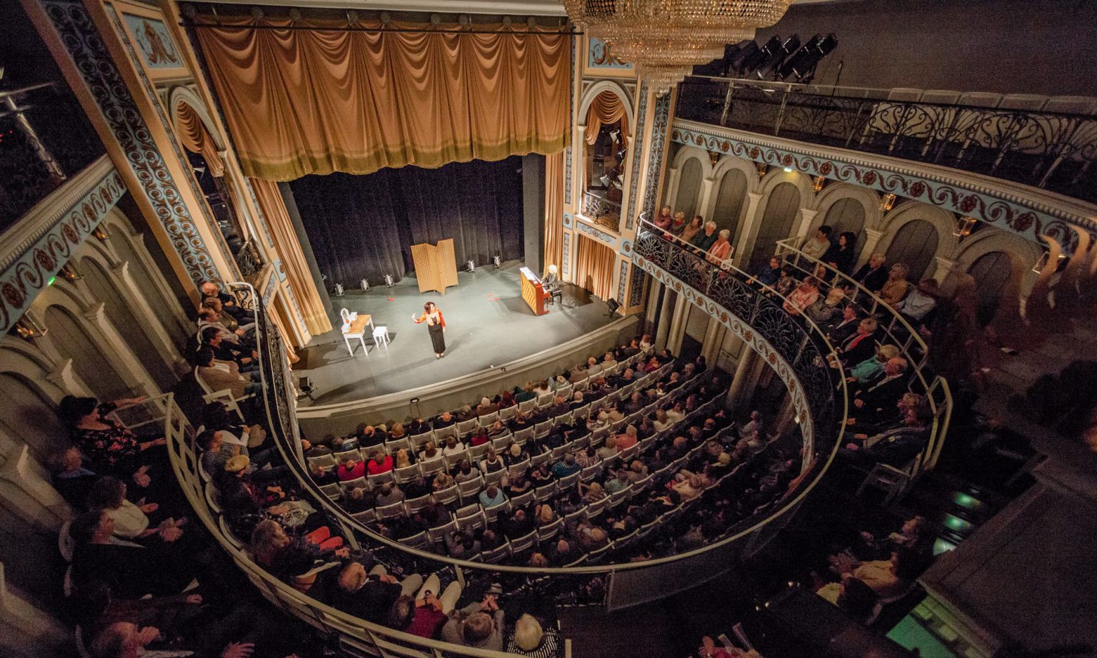 Blick in einen gut besuchten Theaterraum mit Bühne